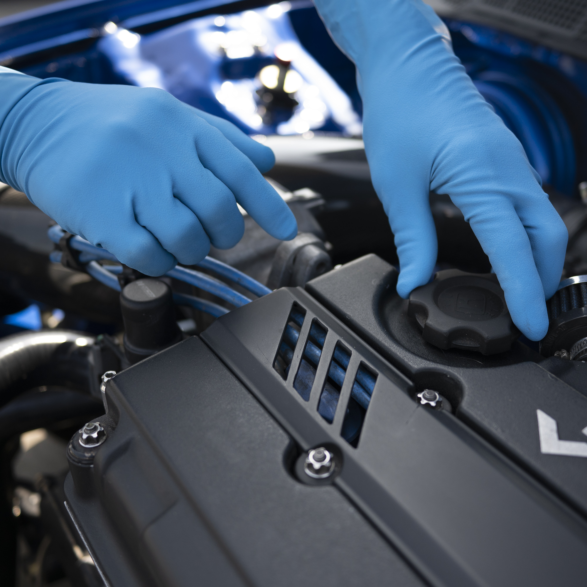 SWIFTEX blue gloves in use while working on an engine